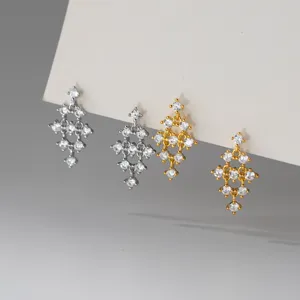 Gros plan détail de boucles d'oreilles clous strass losange géométrique argent et or.