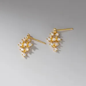 Gros plan détaillé de boucles d'oreilles pendantes dorées au design moderne et élégant.