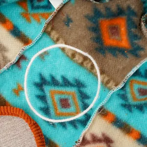 Detail shot of pet fleece onesie featuring vibrant tribal geometric pattern and plush texture.