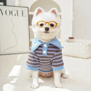 Close-up of a cute puppy wearing a blue and brown striped polo shirt and glasses.