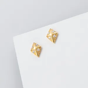 Detailopname van prachtige geometrische ruitvormige oorknopjes met diamant op een witte blok.