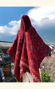 Ethnic style red knitted hooded poncho shawl, cozy autumn winter travel scenic outfit detail.
