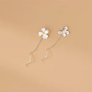 Détail de longues boucles d'oreilles clochettes gardénia, bijoux minimalistes élégants.
