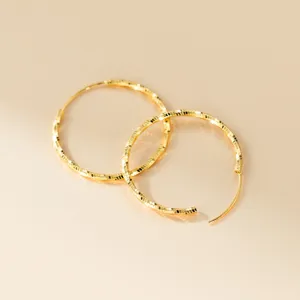 Nahaufnahme der strukturierten großen goldfarbenen Creolen mit feiner facettierter Oberfläche.