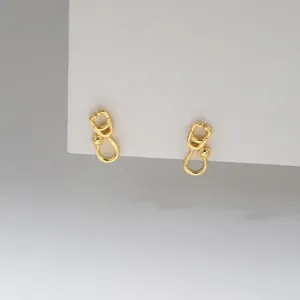 Delicate gold-plated sterling silver stethoscope earrings, minimalist niche jewelry detail view.