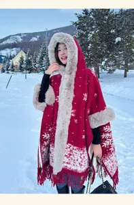 Winter snow scene detail of red hooded cape with plush faux fur trim and snowflake pattern.