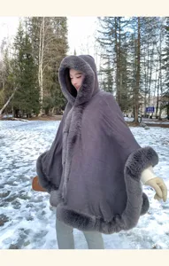 Detailed view of women's winter grey hooded faux fur trim cape coat in snowy outdoor setting.