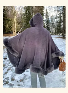 Detailed outdoor view of a dark grey hooded winter cape with cozy faux fur trim in snow.