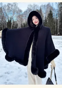 Detailed view of the elegant black hooded cape with plush fur trim in a winter snow scene.