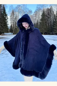 Detail view of women's winter dark blue faux fur hooded cape showing elegant warm cloak design in snow