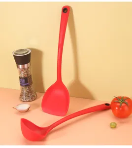Silicone spatula and soup ladle detail view, red heat-resistant kitchenware for cooking.