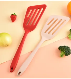 Primo piano dettagliato di spatole forate in silicone rosso e rosa con foro per appendere.