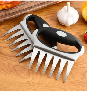 Primer plano de garras de carne de acero inoxidable con mangos ergonomicos para barbacoa.