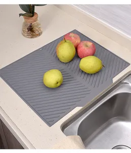 Détail du tapis égouttoir en silicone gris, avec rainures de drainage pour la cuisine et évier.