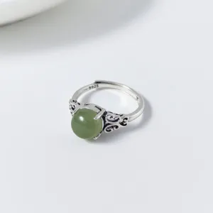 Close-up view of the vintage carved silver ring detail featuring green gemstone accent.