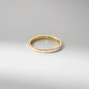 Gros plan détaillé d'un anneau minimaliste plaqué or avec incrustation d'émail blanc.