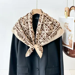 Close-up detail of the elegant beige and brown patterned square silk scarf displayed on a blazer.