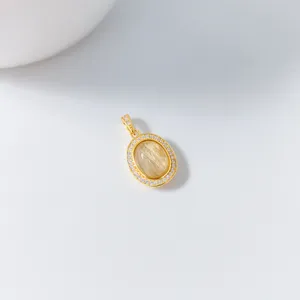Detailaufnahme des eleganten ovalen goldenen Rutilquarz-Anhängers mit funkelndem Zirkon.