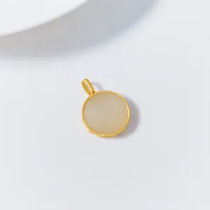 Gros plan détaillé d'un pendentif rond en jade de Hetian de style rétro avec une bordure dorée.