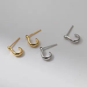 Vista di dettaglio di orecchini a lobo irregolari a J in argento e oro, stile minimal chic.