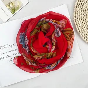 Nahaufnahme des roten Chiffonschals mit Blumenmuster, stilvoll als Rose arrangiert auf Magazin.