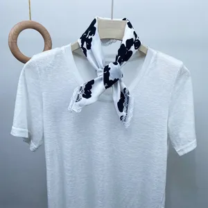 Close-up detail of black and white printed silk square scarf with delicate lace trim.