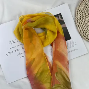 Gradient chiffon silk scarf detail showing soft yellow green floral pattern and lightweight texture.