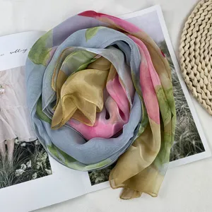 Elegant gradient silk scarf featuring soft watercolor floral tones, artfully rolled for a chic display.