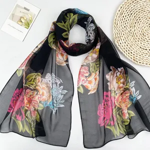 Nahaufnahme Detail eines schwarzen Damen Chiffonschals mit bunten Pfingstrosenmuster im Frühling.