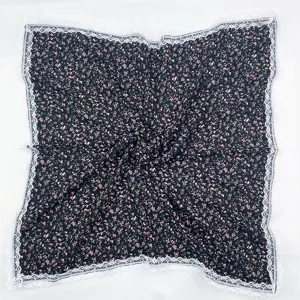 Detailed view of women's floral square scarf with delicate white lace trim edge.