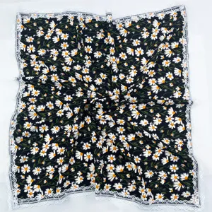Detail view of black floral square scarf with daisy pattern and white lace trim.