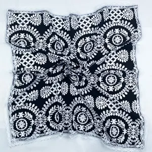 Detailed view of the elegant black square scarf featuring white floral pattern and lace trim.