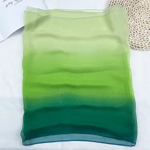 Detail view of a lightweight gradient green chiffon scarf, showing soft sheer fabric texture.