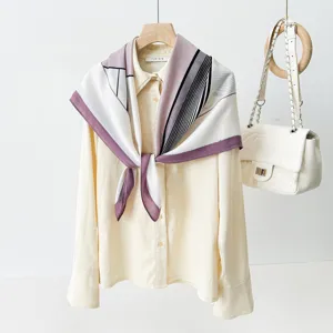 Geometric print silk square scarf detail styled on beige blouse with elegant color block.