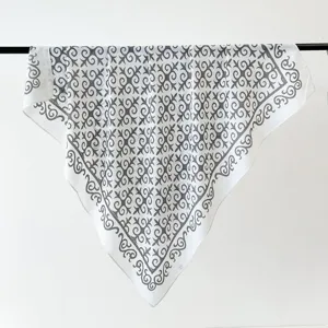 Detailed view of luxury white square silk scarf with grey vintage geometric pattern.