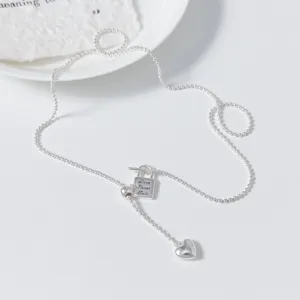 Silver Y-necklace detail close up, heart pendant and small lock design, elegant jewelry.