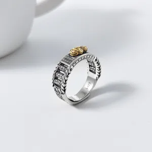Close-up detail of vintage sterling silver ring featuring golden pixiu and spinning prayer wheel.