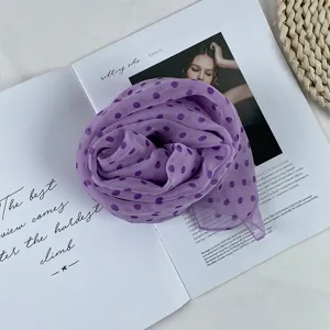 Close-up detail of a soft purple polka dot chiffon scarf, elegant neck accessory for women.