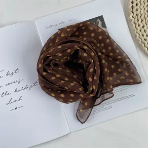 Close-up detail of the brown polka dot chiffon scarf, elegant accessory for summer styling.