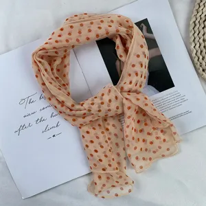 Close-up of lightweight chiffon polka dot scarf in peach color, delicate sheer summer fashion.