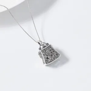 Detailed close-up of a vintage sterling silver hollow handbag pendant necklace, exquisite.