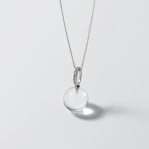 Gros plan du pendentif boule de cristal montrant une texture transparente et chaîne.