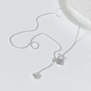 Detail shot of the sweet and cool silver Y-necklace featuring a delicate heart charm and lock.