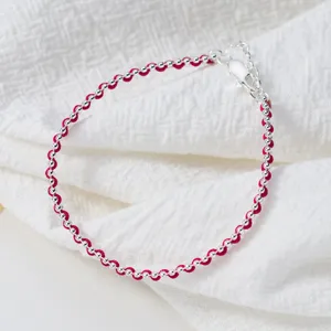 Detailaufnahme eines minimalistischen S925 Silber Perlen gewebten roten Kordelarmbands, Textur.