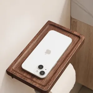 Wooden toilet paper holder with storage shelf and phone tray for stylish bathroom use.