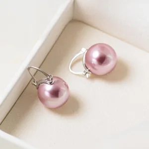 Nahaufnahme von eleganten rosa Perlenohrringen mit Silberverschlüssen in weißer Schmuckbox.