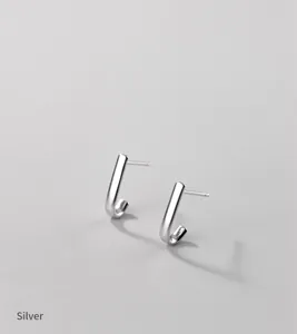 Boucles d'oreilles puces ligne courbée en argent s925 détail gros plan, design élégant.