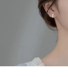 Gros plan de la vue de détail d'une boucle d'oreille minimaliste en argent sur le lobe.
