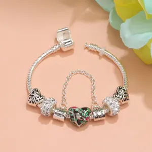 Detalle de pulsera con cadena de serpiente de plata, cuentas de cristal y colgante de corazon.