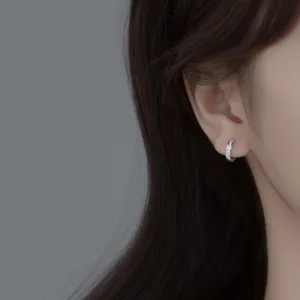 Close-up detail view of S925 silver pave cubic zirconia huggie hoop earrings worn on ear.